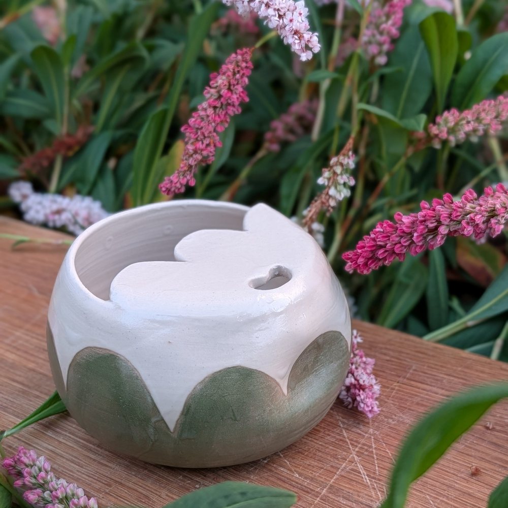 Lidded travel mug with a scalloped green band and a heart-shaped sip hole
