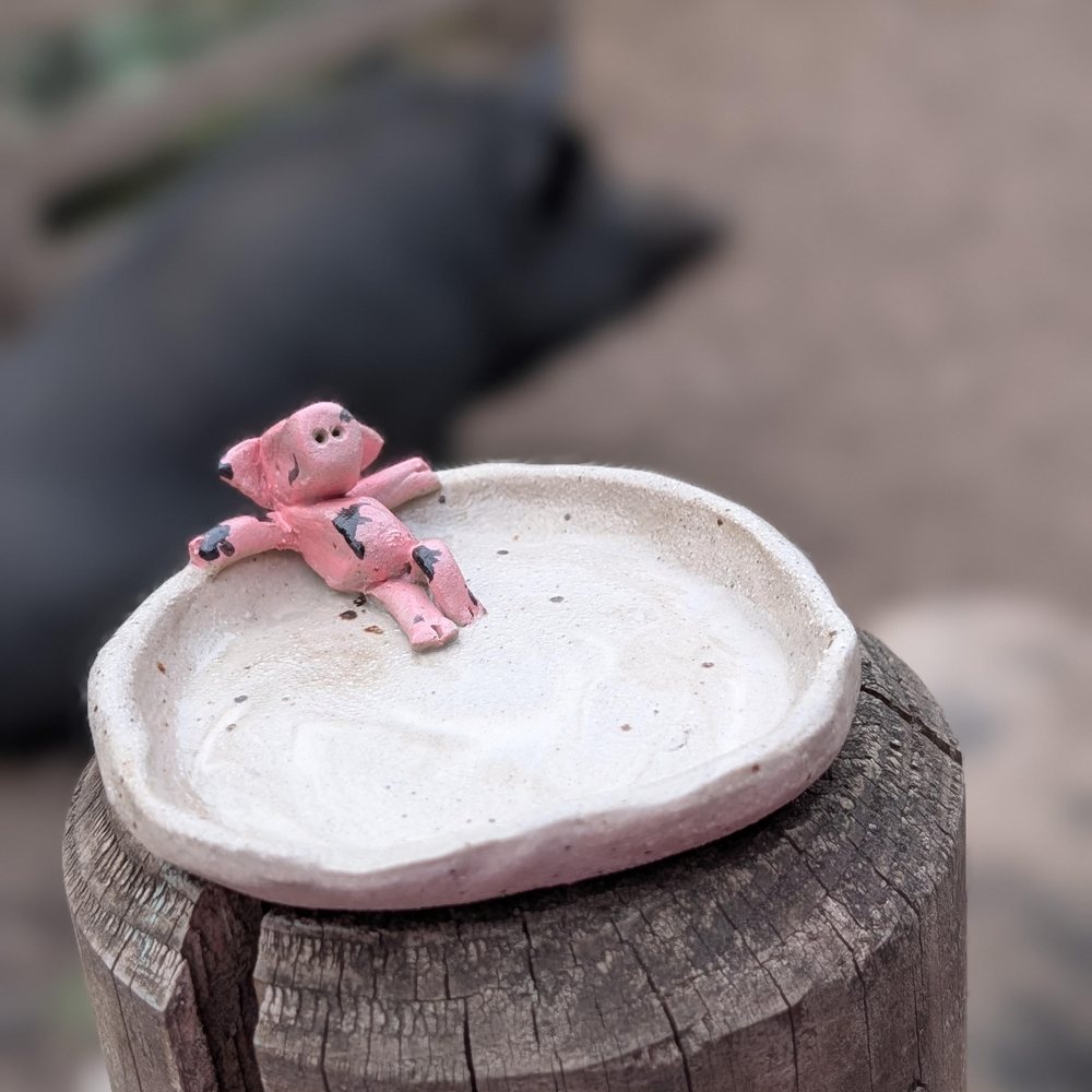 Small ceramic trinket dish with a pink pig resting on the edge